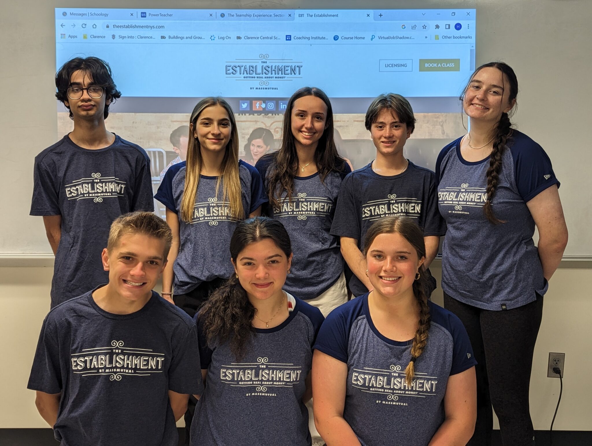 Students smiling in front of projector screen